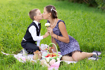 Image showing Little boy and teen age girl having picnic outdoors