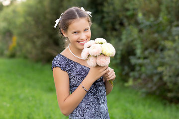 Image showing beautiful teen age girl holding flowers outdoors