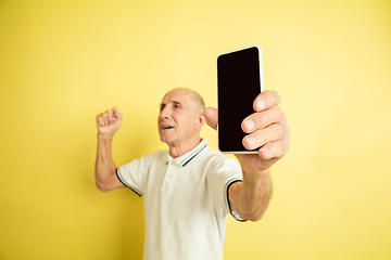 Image showing Caucasian senior man\'s portrait isolated on yellow studio background