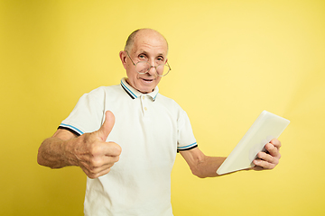 Image showing Caucasian senior man\'s portrait isolated on yellow studio background