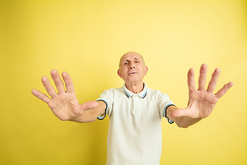 Image showing Caucasian senior man\'s portrait isolated on yellow studio background