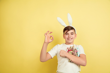 Image showing Easter bunny boy with bright emotions on yellow studio background