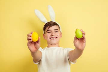 Image showing Easter bunny boy with bright emotions on yellow studio background