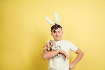 Image showing Easter bunny boy with bright emotions on yellow studio background