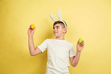 Image showing Easter bunny boy with bright emotions on yellow studio background