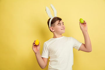 Image showing Easter bunny boy with bright emotions on yellow studio background