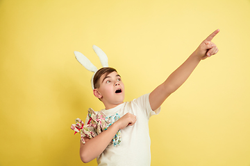 Image showing Easter bunny boy with bright emotions on yellow studio background