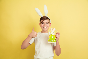 Image showing Easter bunny boy with bright emotions on yellow studio background