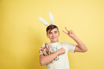 Image showing Easter bunny boy with bright emotions on yellow studio background