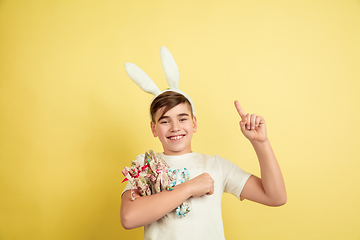 Image showing Easter bunny boy with bright emotions on yellow studio background