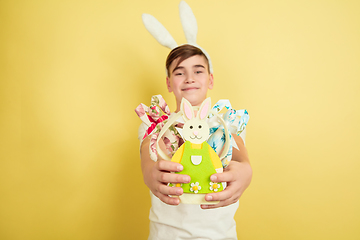 Image showing Easter bunny boy with bright emotions on yellow studio background