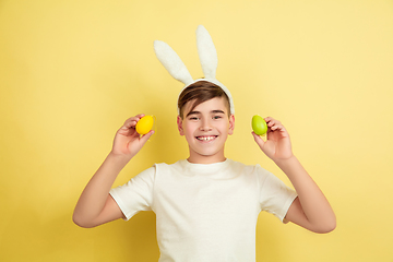 Image showing Easter bunny boy with bright emotions on yellow studio background