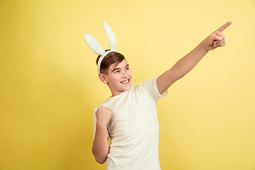 Image showing Easter bunny boy with bright emotions on yellow studio background