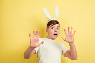 Image showing Easter bunny boy with bright emotions on yellow studio background