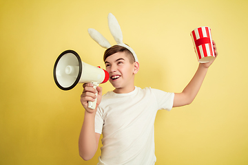 Image showing Easter bunny boy with bright emotions on yellow studio background