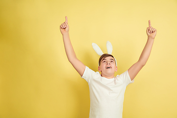 Image showing Easter bunny boy with bright emotions on yellow studio background