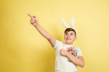 Image showing Easter bunny boy with bright emotions on yellow studio background