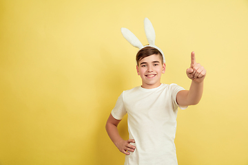 Image showing Easter bunny boy with bright emotions on yellow studio background