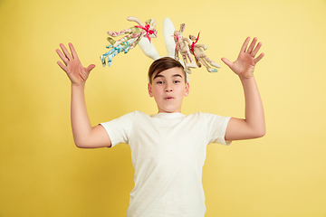 Image showing Easter bunny boy with bright emotions on yellow studio background