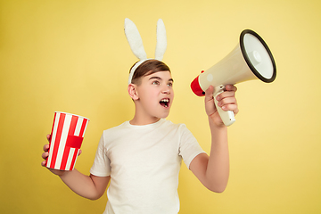Image showing Easter bunny boy with bright emotions on yellow studio background