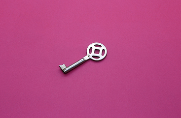 Image showing Old metal key on bright crimson paper background