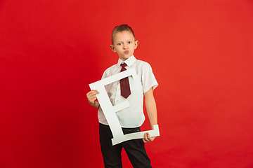 Image showing Valentine\'s day celebration, happy caucasian boy holding letter on red background