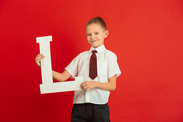 Image showing Valentine\'s day celebration, happy caucasian boy holding letter on red background