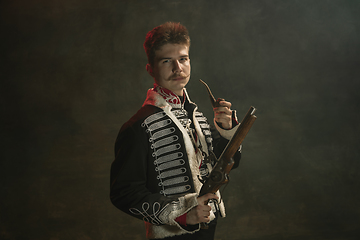 Image showing Young man in suit as royal person isolated on dark green background. Retro style, comparison of eras concept. Beautiful male model like historical character, monarch, old-fashioned.