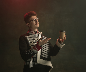 Image showing Young man in suit as royal person isolated on dark green background. Retro style, comparison of eras concept. Beautiful male model like historical character, monarch, old-fashioned.