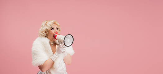 Image showing Portrait of young woman in white dress on coral pink background. Female model as a legendary actress. Pin up. Concept of comparison of eras, modern, fashion, beauty.