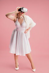 Image showing Portrait of young woman in white dress on coral pink background. Female model as a legendary actress. Pin up. Concept of comparison of eras, modern, fashion, beauty.