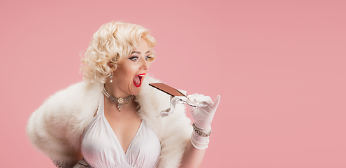 Image showing Portrait of young woman in white dress on coral pink background. Female model as a legendary actress. Pin up. Concept of comparison of eras, modern, fashion, beauty.