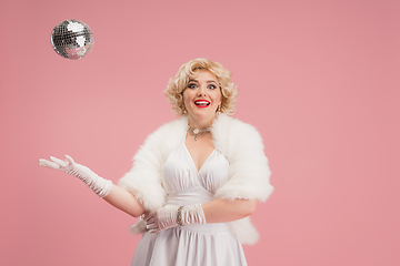 Image showing Portrait of young woman in white dress on coral pink background. Female model as a legendary actress. Pin up. Concept of comparison of eras, modern, fashion, beauty.