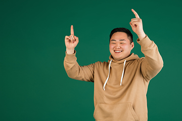 Image showing Asian man\'s portrait isolated over green studio background with copyspace