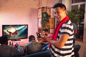 Image showing Group of friends watching TV, sport match together. Emotional man cheering for favourite team, celebrating successful betting. Concept of friendship, leisure activity, emotions