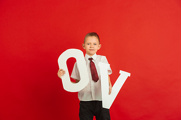 Image showing Valentine\'s day celebration, happy caucasian boy holding letter on red background