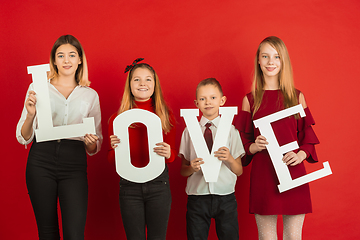 Image showing Valentine\'s day celebration, happy caucasian teens holding letters on red background