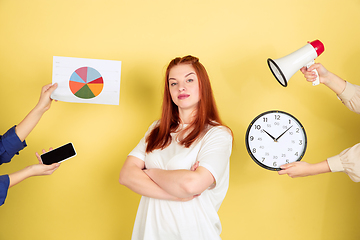 Image showing Caucasian young woman\'s portrait on yellow background, too much tasks