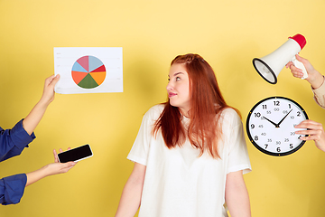 Image showing Caucasian young woman\'s portrait on yellow background, too much tasks