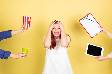 Image showing Caucasian young woman\'s portrait on yellow background, too much tasks