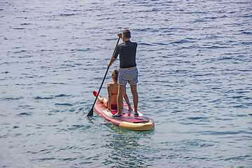 Image showing Young couple on stand up paddleboard surfboard surfing together