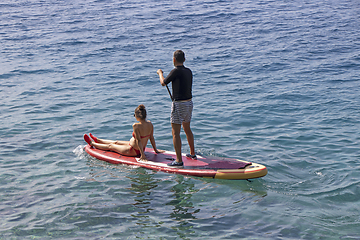 Image showing Young couple on stand up paddleboard surfboard surfing together