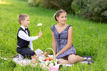 Image showing Little boy and teen age girl having picnic outdoors