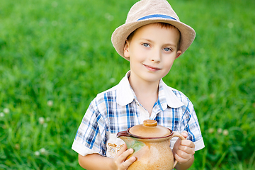 Image showing handsome little boy with jug standing outdoors