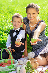 Image showing Little boy and teen age girl having picnic outdoors