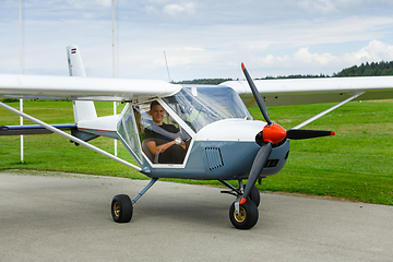 Image showing outdoor shot of young man in small plane cockpit