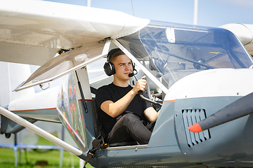 Image showing outdoor shot of young man in small plane cockpit