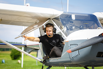 Image showing outdoor shot of young man in small plane cockpit