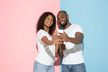 Image showing Young emotional man and woman on pink and blue background