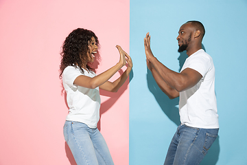 Image showing Young emotional man and woman on pink and blue background